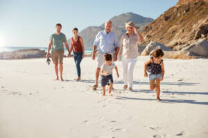 Three generations of family walking together on the sand, the Aged Parent visa 804 lets parents apply from within Australia