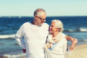 A happy senior couple hugging on a summer beach in Australia, the Contributory Aged Parent temporary visa 884 for parents already onshore