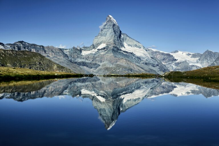 The Matterhorn mirrored perfectly in a still alpine lake near Zermatt, image of precision for Swiss residence by lump sum taxation