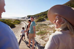 Grandparents, parents and children walking together on an Australian beach, the Sponsored Parent temporary visa 870 reunites families for up to ten years