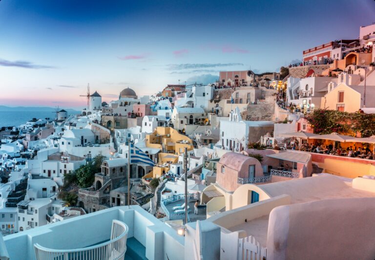 Whitewashed houses and blue domes of Oia glowing at dusk on the Santorini caldera, an icon of the Greece golden visa lifestyle