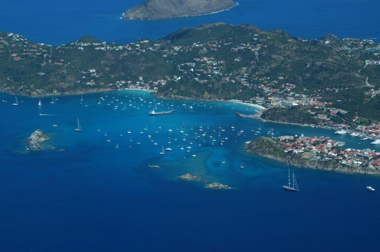 Aerial view of St Kitts and Nevis with yachts scattered across a deep blue harbour beside green volcanic hills, setting for the original citizenship by investment programme